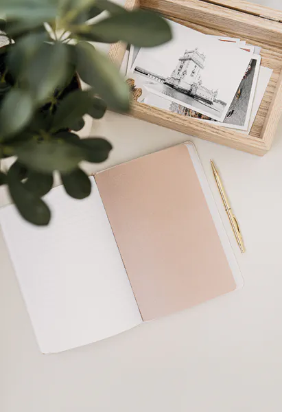 Flat lay image of a blank journal, a pen, and a shoebox filled with black and white photos. In our life coaching sessions together, I will guide you in journaling exercises to help you achieve a better work life balance.