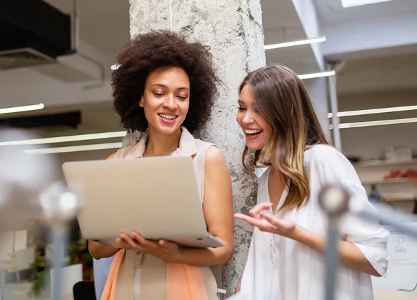 Two employees looking at a laptop choosing between the different wellness & health coaching options offered by their workplace.